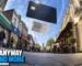 Fisheye street split between everyday shops and aspirational retail beneath a floating credit card